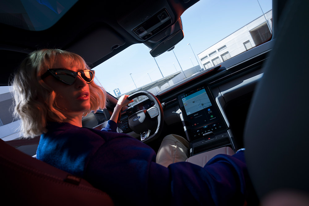 Persona al posto di guida di una Ford Capri, con volante e grande touchscreen SYNC Move visibili.
