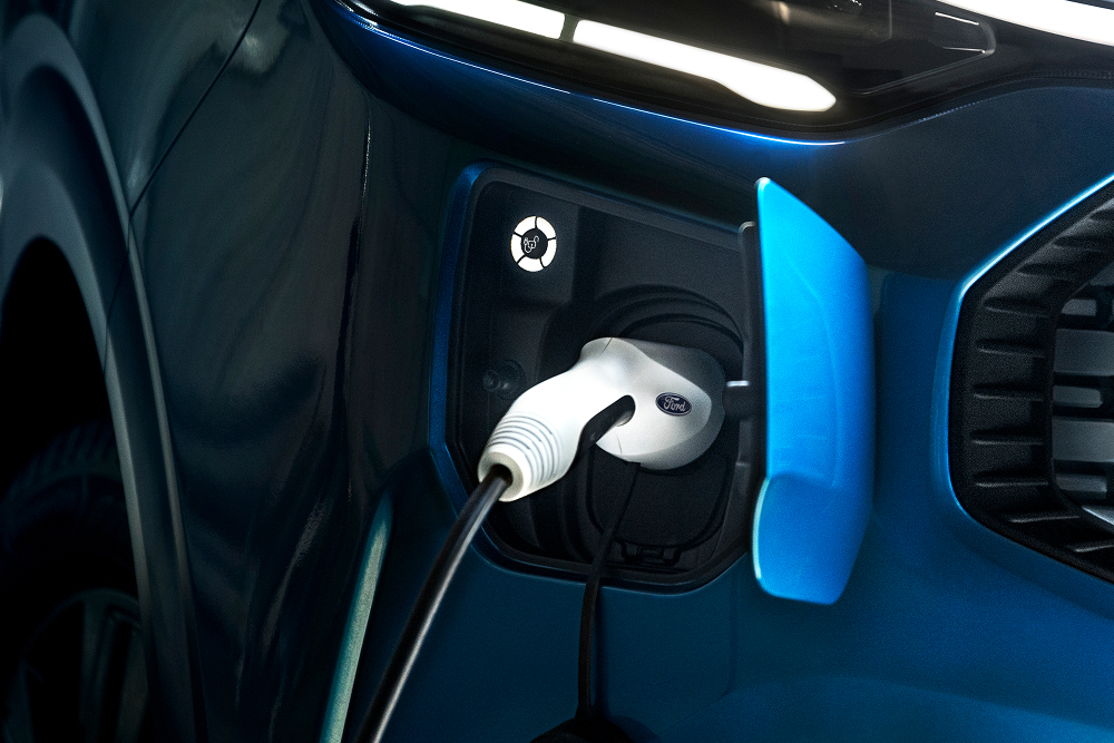 Un primo piano di un cavo di ricarica elettrico collegato a un furgone elettrico Ford E-Transit Custom.