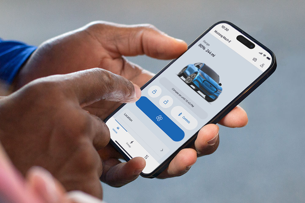 Primo piano di un iPhone che mostra la Ford app, con immagine di un Ford Mustang Mach-E e vari pulsanti dell'app.