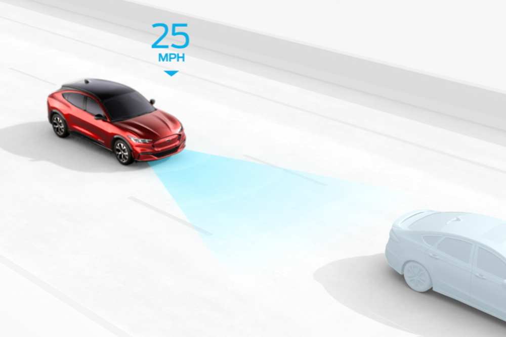 Una grafica mostra una Ford Mustang Mach-E rossa con un cono sensore, che segue un'auto grigia a 25 MPH, spiegando l'Intelligent Cruise Control