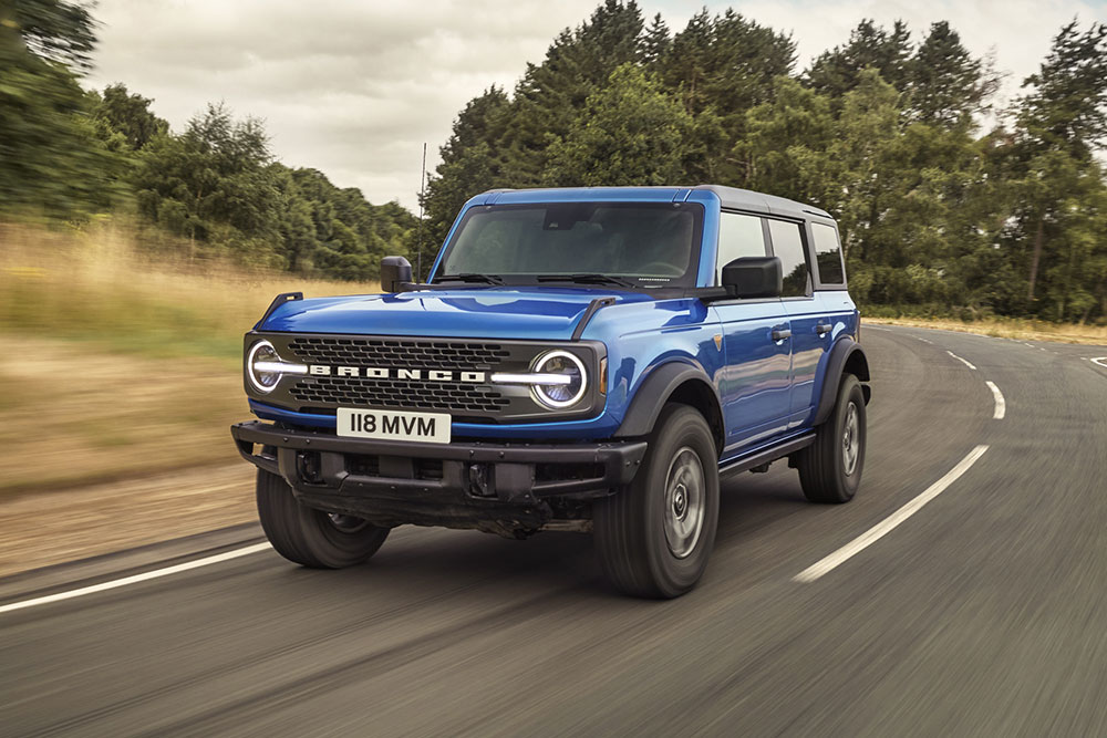 Vista frontale del nuovo Ford Bronco blu che percorre una strada di campagna.