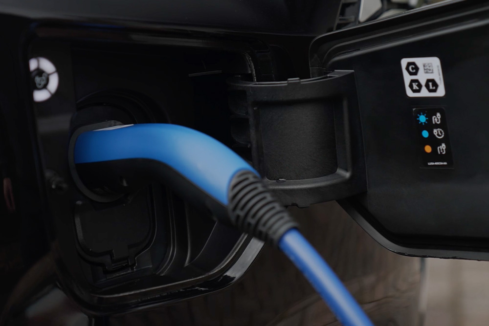 Primo piano di un cavo di ricarica blu collegato a una porta di ricarica per veicoli elettrici.