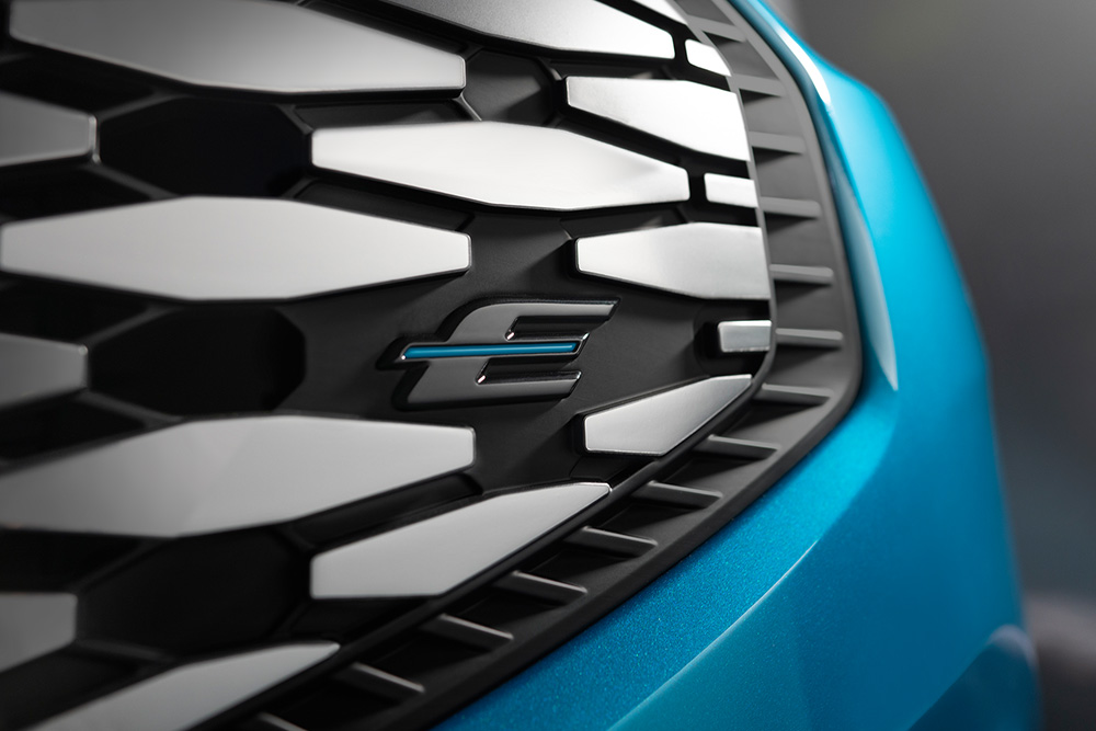 Primo piano della griglia del Ford E-Tourneo Custom, con l'esclusivo logo "E" blu dei veicoli elettrici Ford.