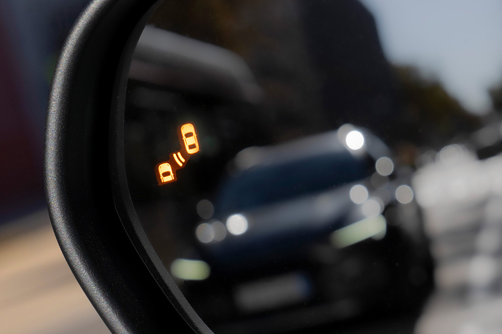 Primo piano dell'avviso del Sistema di assistenza angolo cieco nello specchietto laterale del Ford Puma Gen-E®.