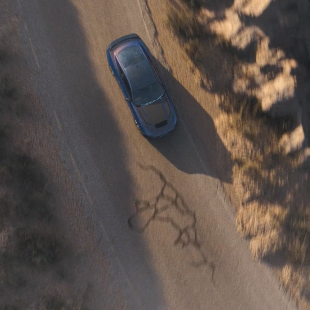 Una foto dall'alto di una Ford Mustang Dark Horse Fastback con carrozzeria Blue Ember mentre percorre una strada di montagna.