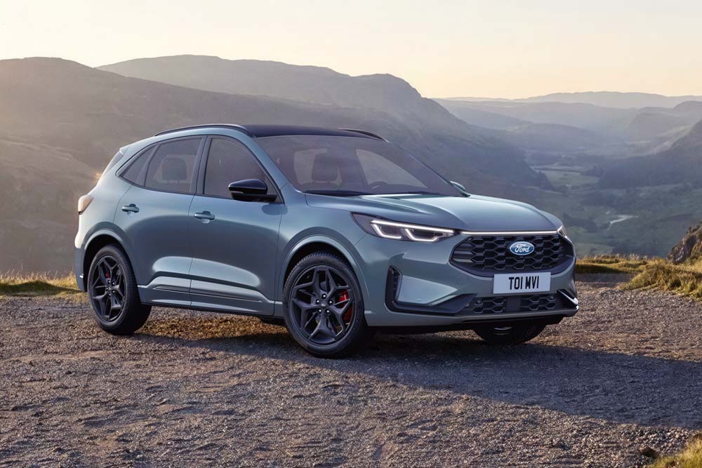 SUV Ford Kuga blu parcheggiato con montagne nel background.