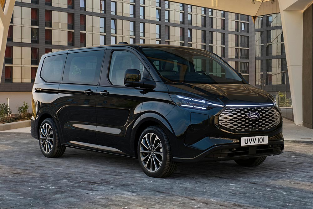 Un Ford E-Tourneo Custom nero parcheggiato di fronte a un edificio moderno.