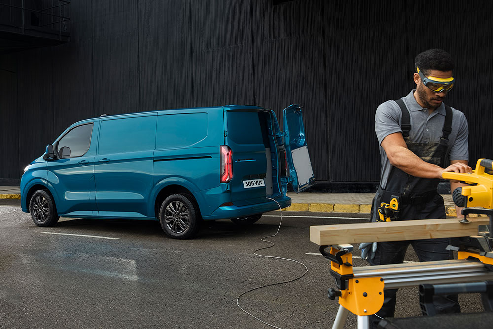 Un furgone elettrico Ford E-Transit Custom blu e una persona che utilizza utensili elettrici.
