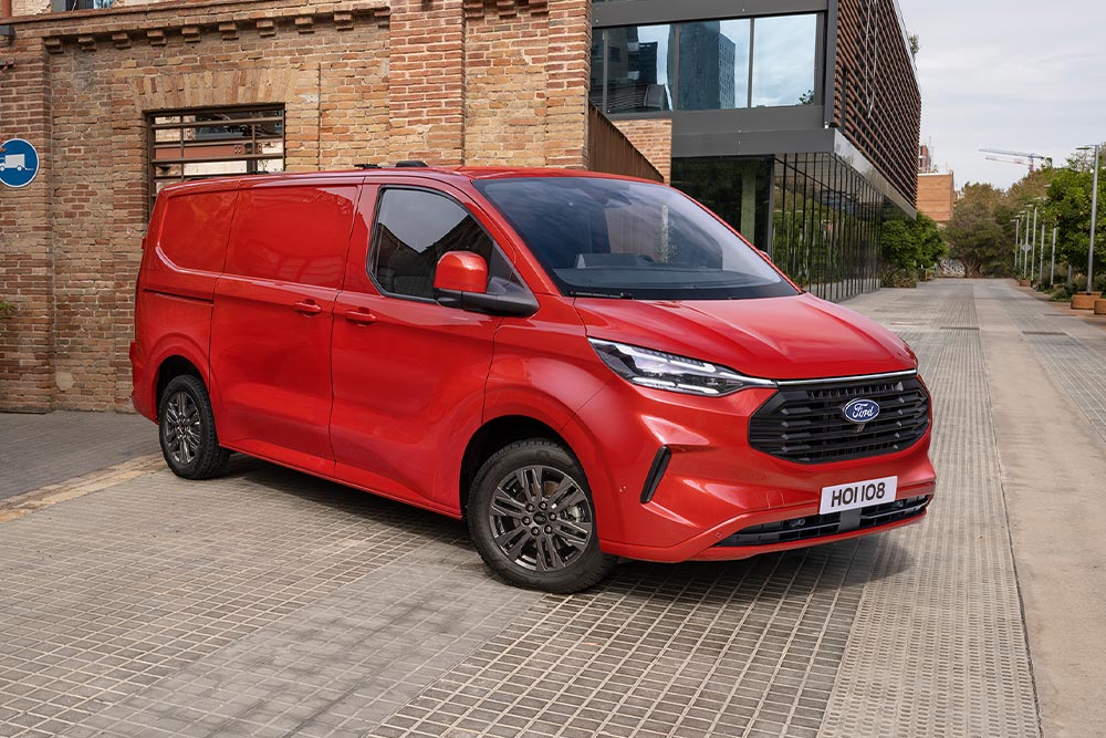 Un corriere carica i pacchi in un Ford Transit Custom rosso.