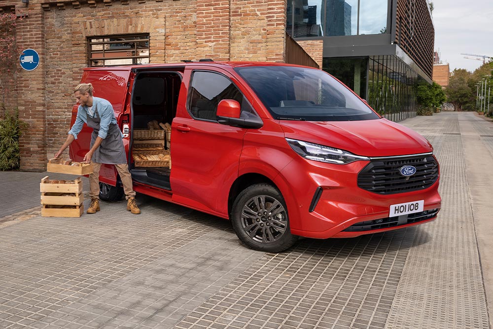 Un corriere carica i pacchi in un Ford Transit Custom rosso.