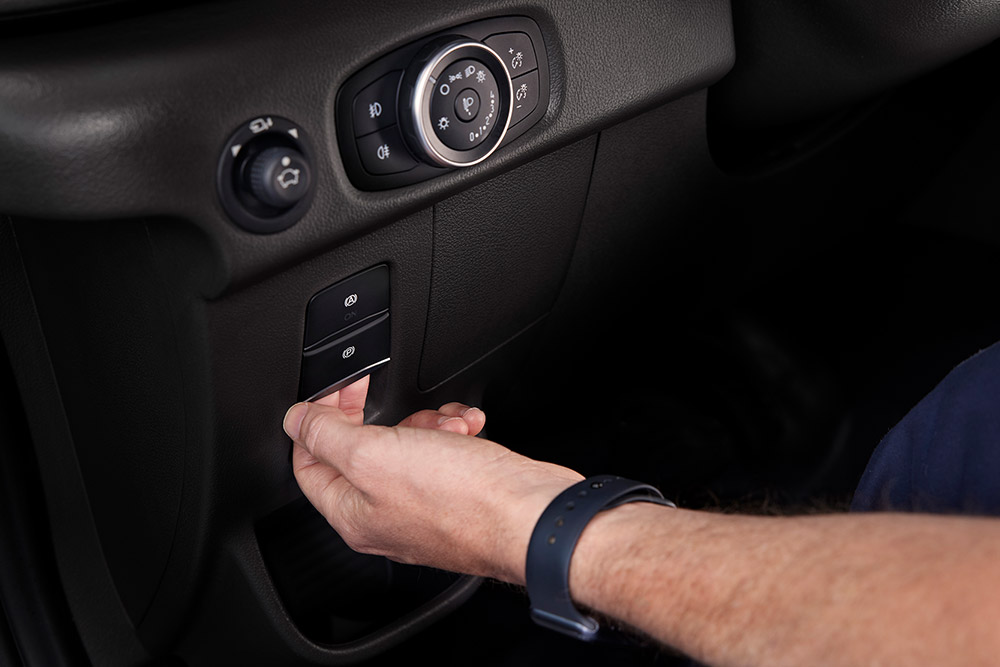 Prima mano di una mano che preme un pulsante sul cruscotto di un furgone elettrico Ford E-Transit.