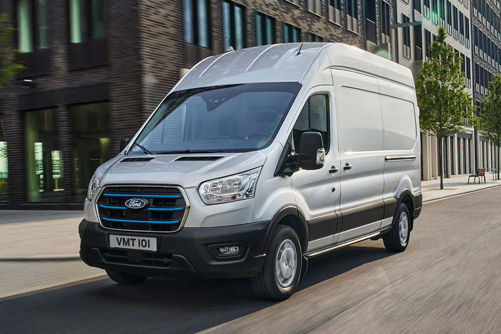 Un furgone Ford E-Transit versione argento che percorre una strada cittadina.