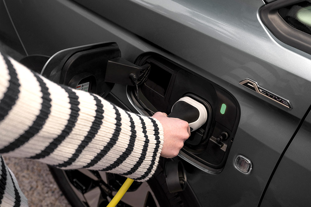 Una persona collega un cavo di ricarica a un Ford Transit Connect Plug-in Hybrid.