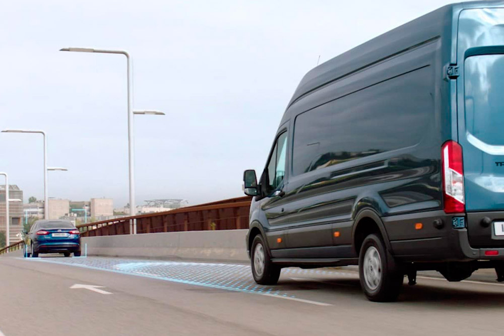 Furgone Ford Transit versione blu con le strisce blu sulla strada che segnalano l'utilizzo di Sistemi di assistenza alla guida.