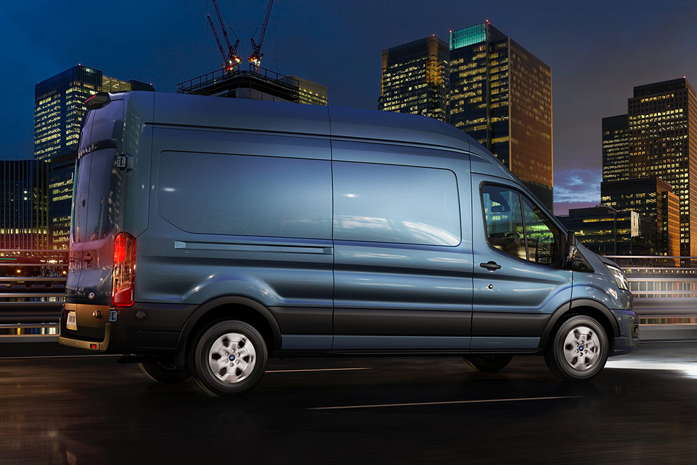Ford Transit blu che percorre una strada cittadina di notte. 