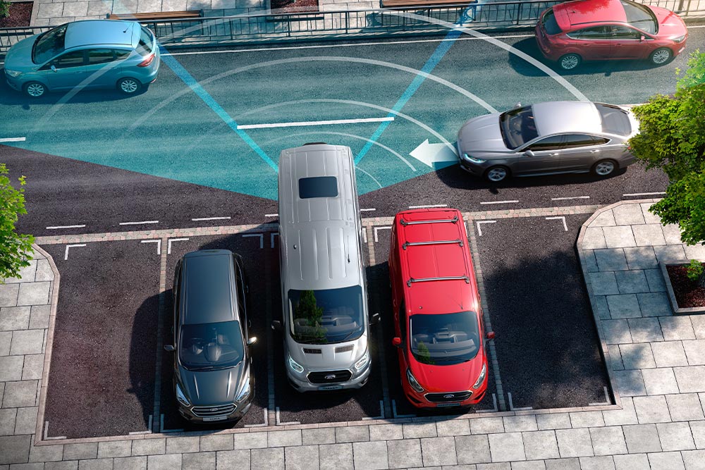 Furgone Transit Van versione argento che fa retromarcia, con le strisce blu che segnalano l'utilizzo del sensore di parcheggio posteriore.