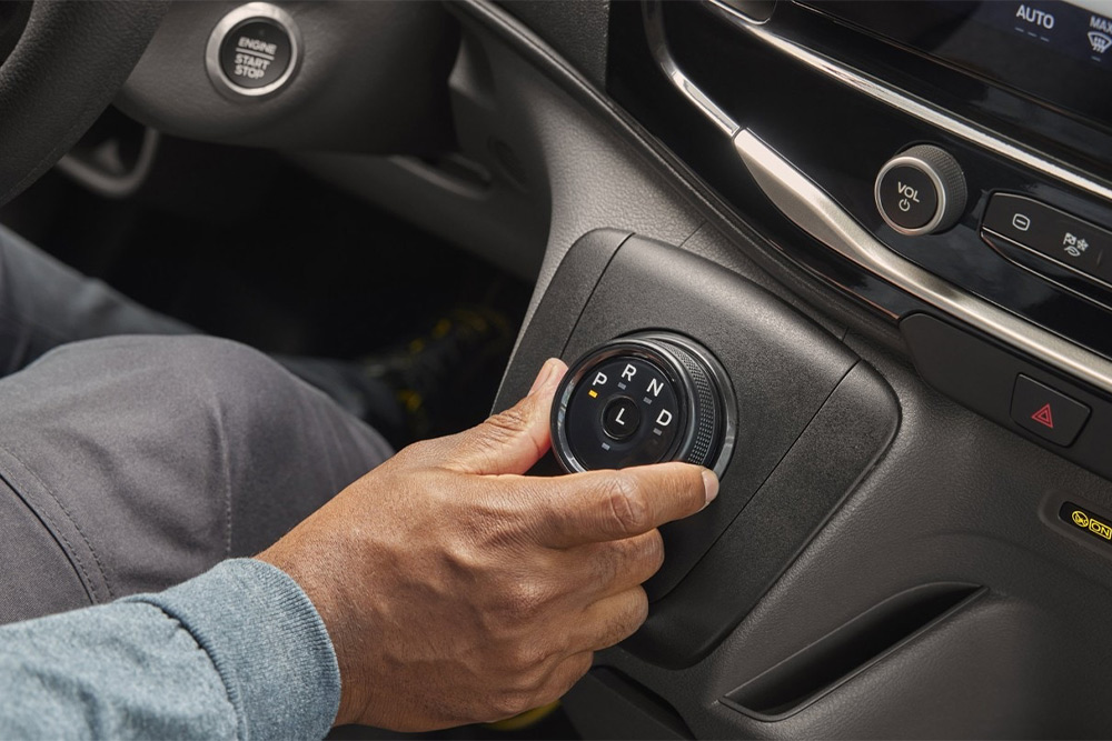 Mano che aziona il cambio rotativo nella console centrale di un furgone Ford Transit.