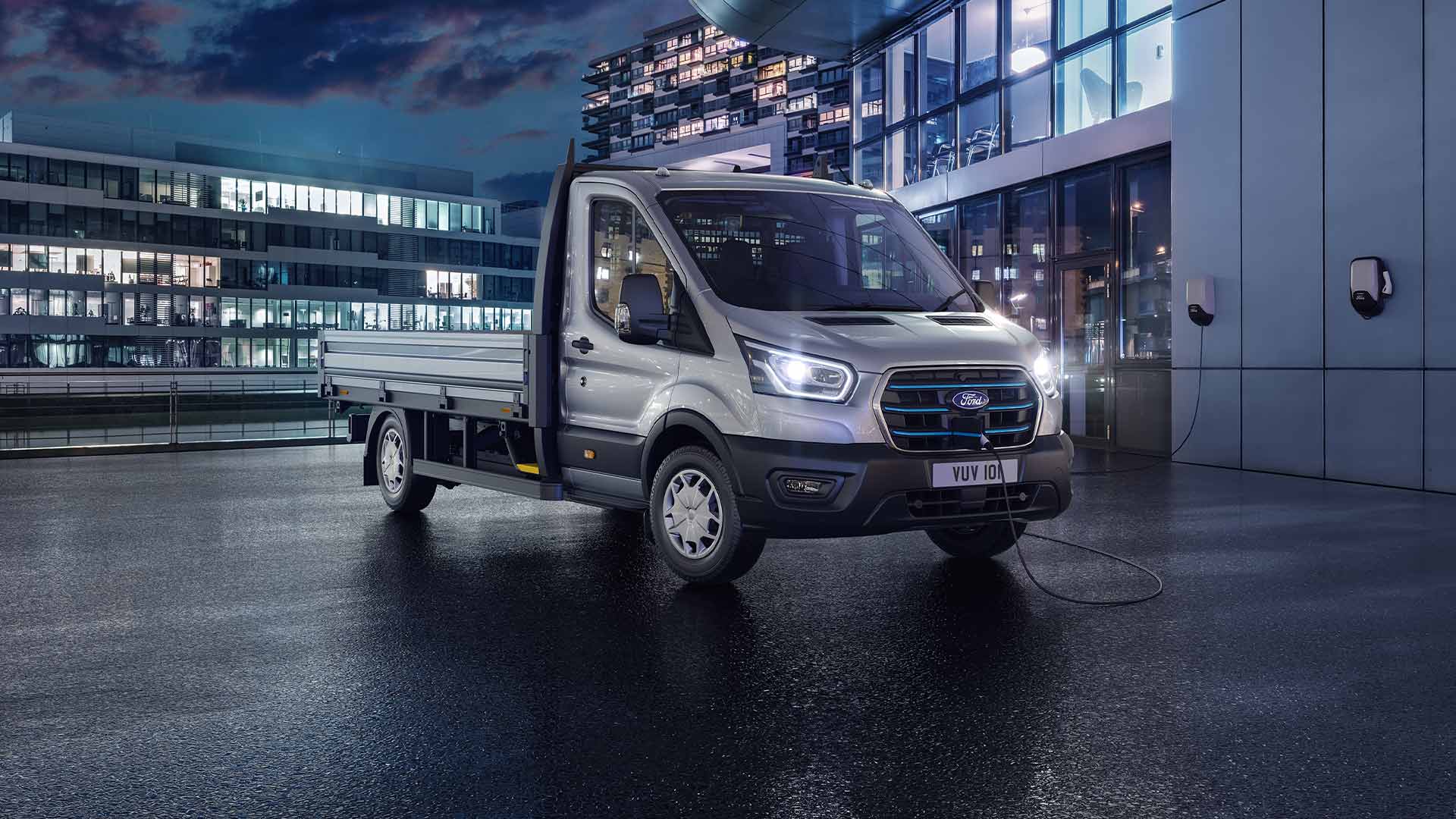 Ford Transit Chassis versione argento parcheggiato di fronte a un edificio moderno di notte.