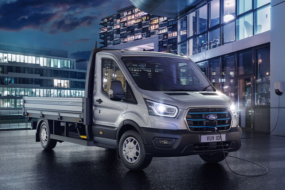 Ford Transit Chassis versione argento parcheggiato di fronte a un edificio moderno di notte.