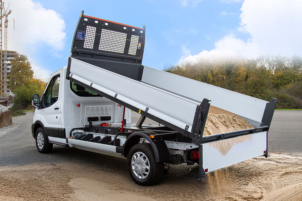 Telaio cabina Ford Pro bianco con pianale rialzato parcheggiato in un cantiere.
