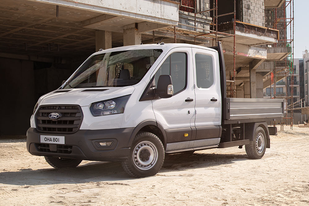 Telaio cabina Ford Pro bianco parcheggiato in un cantiere accanto a due operai edili.