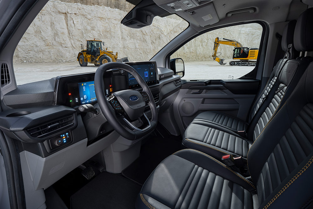 Vista sugli interni di un furgone Ford Transit Custom, che mostra il cruscotto, il volante e i sedili.