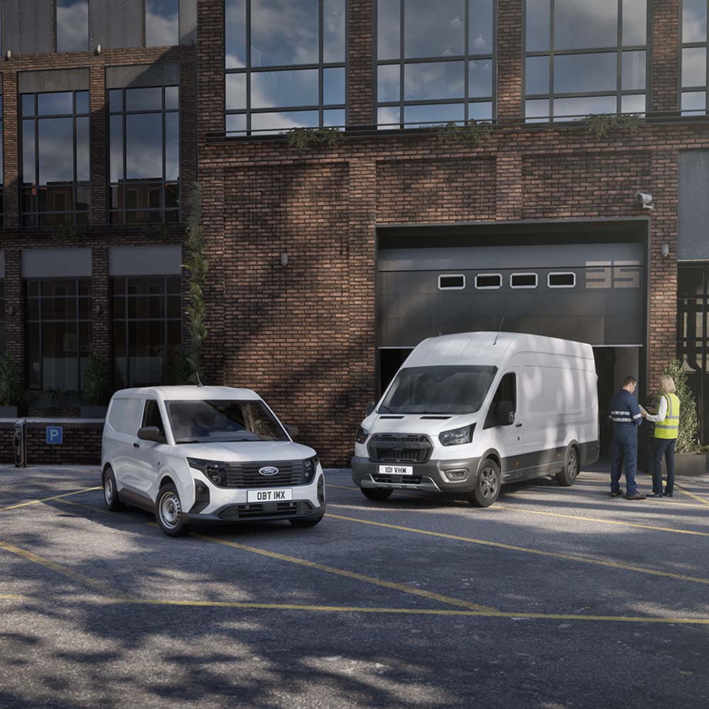 Due furgoni Ford bianchi parcheggiati di fronte a un edificio moderno e due persone che chiacchierano di fianco ai veicoli.
