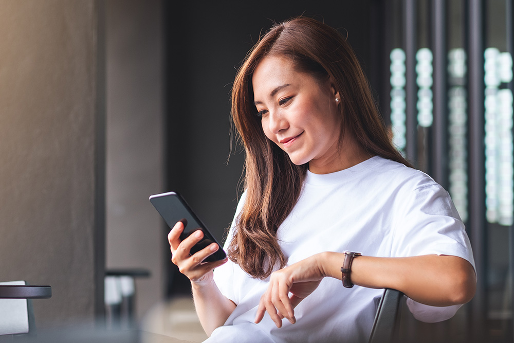 Donna che controlla gli avvisi in tempo reale dall'app FordPass sul suo dispositivo mobile.