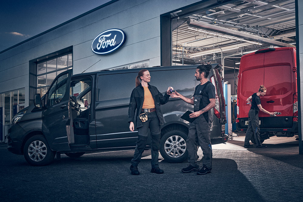 Cliente e tecnico Ford si scambiano le chiavi di un furgone davanti a una concessionaria Ford.