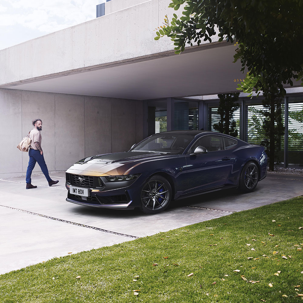 Un Ford Mustang Dark Horse parcheggiato accanto a una persona che cammina verso casa